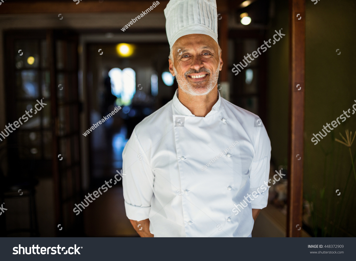 stock-photo-portrait-of-chef-standing-with-hands-behind-back-in-restaurant-448372909